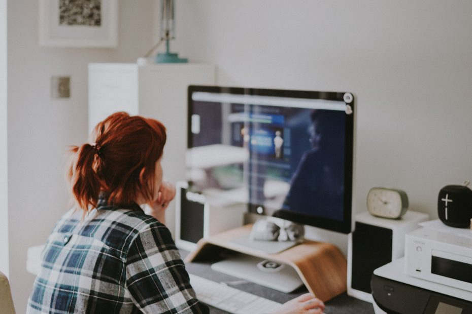 Woman in checked shirt working from home at a computer.